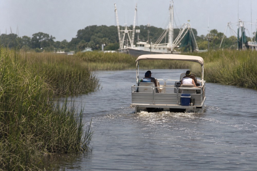Rental pontoon boat cruising a tidal creek near Charleston, no text, no logos, no people