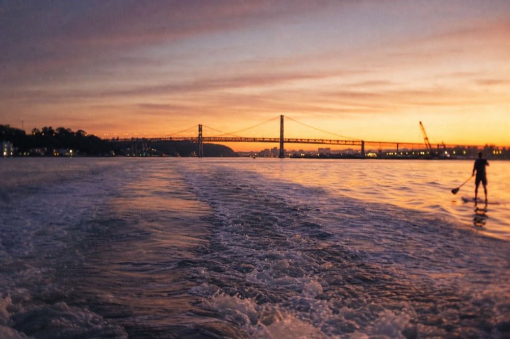 Boat wake crossing golden light on Charleston Harbor at sunset, no text, no logos, no people