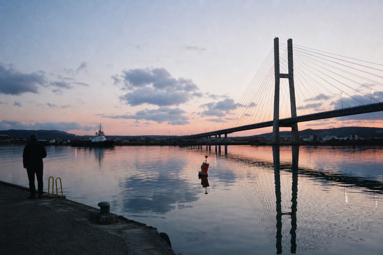 Calm harbor water reflecting the Ravenel Bridge at dusk, no text, no logos, no people
