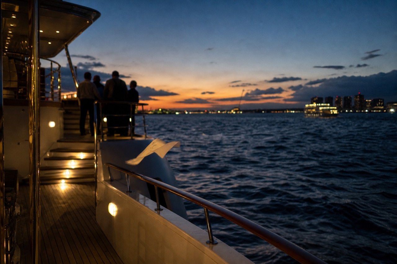 A dinner cruise boat lit for the evening on Charleston Harbor at dusk, no text, no logos, no people