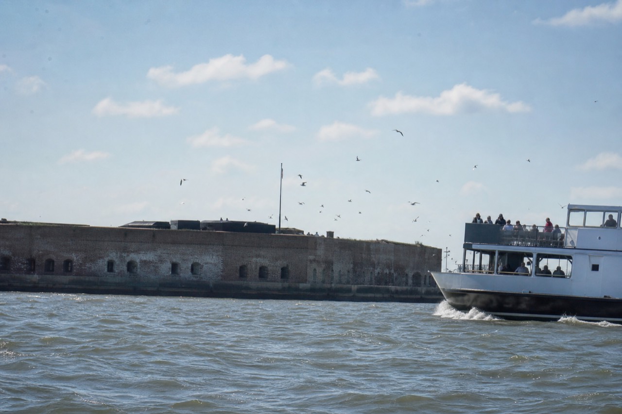 Fort Sumter National Monument seen from the water with a harbor tour boat passing by, no text, no logos, no people.