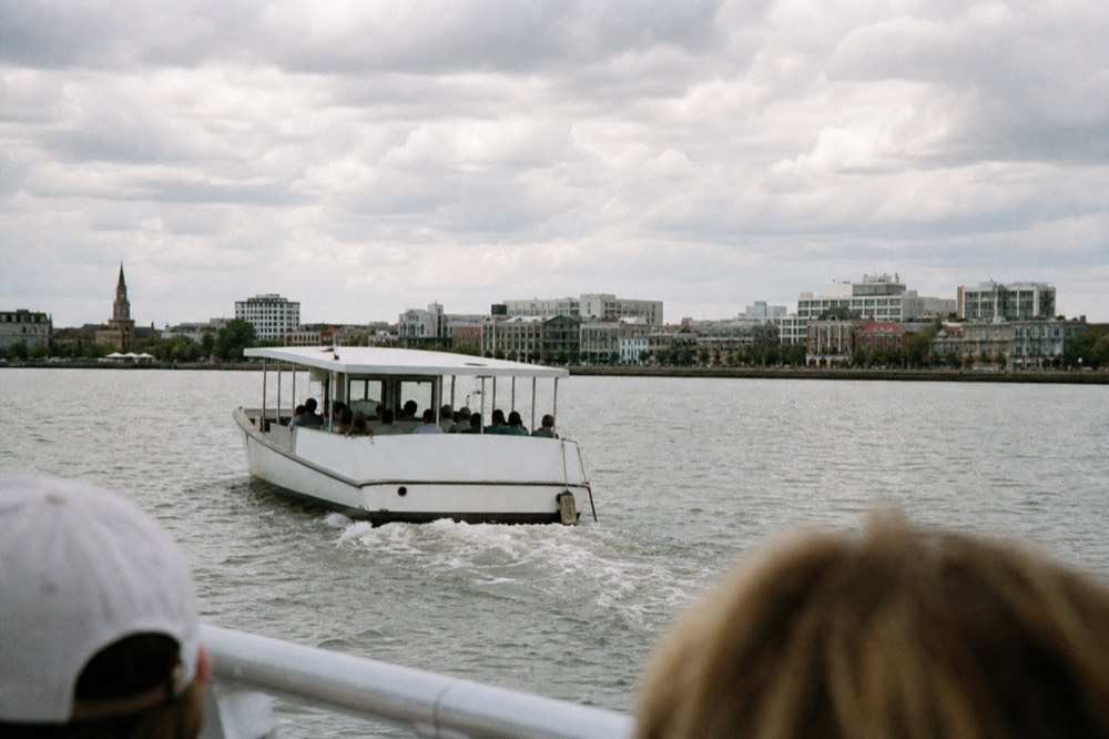 A small sightseeing boat cruising Charleston Harbor past the downtown skyline, no text, no logos, no people