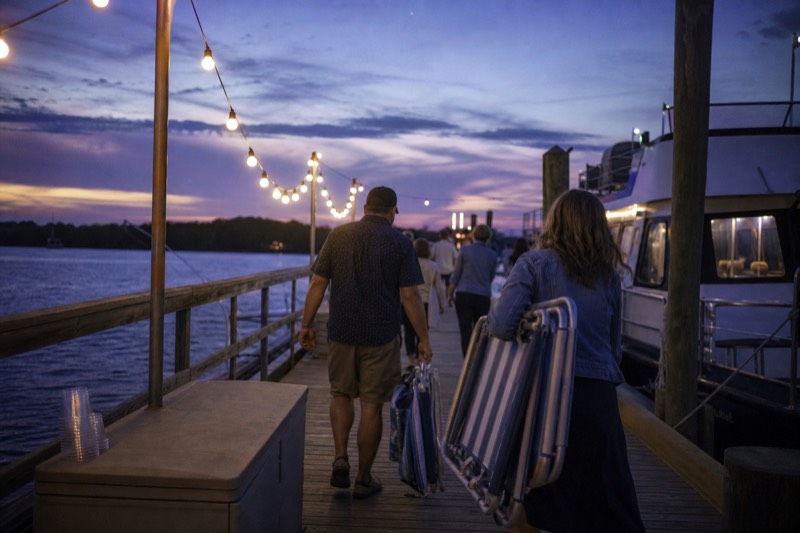 Themed evening cruise boat boarding at dusk with string lights along the Charleston harbor dock