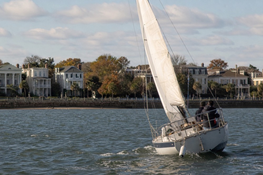 A small sailing yacht under way on open harbor water near the Battery, no text, no logos, no people.