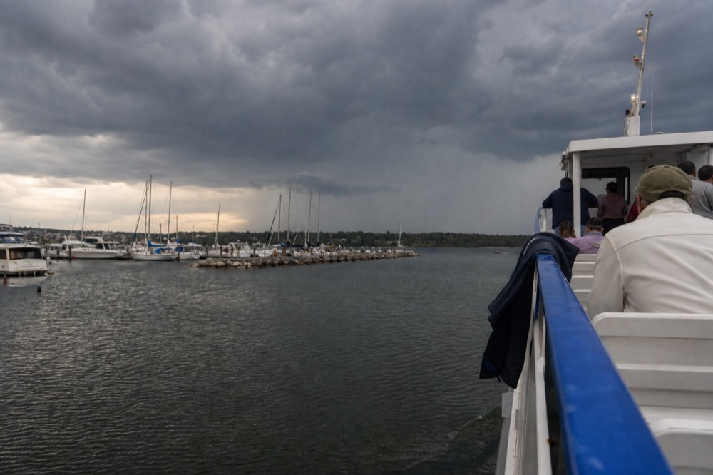 Clouds gathering over Charleston harbor with a tour boat heading back toward the marina, no text, no logos, no people