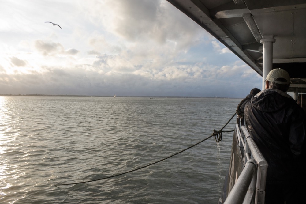 A wide view of Charleston harbor under dramatic but clearing skies, no text, no logos, no people