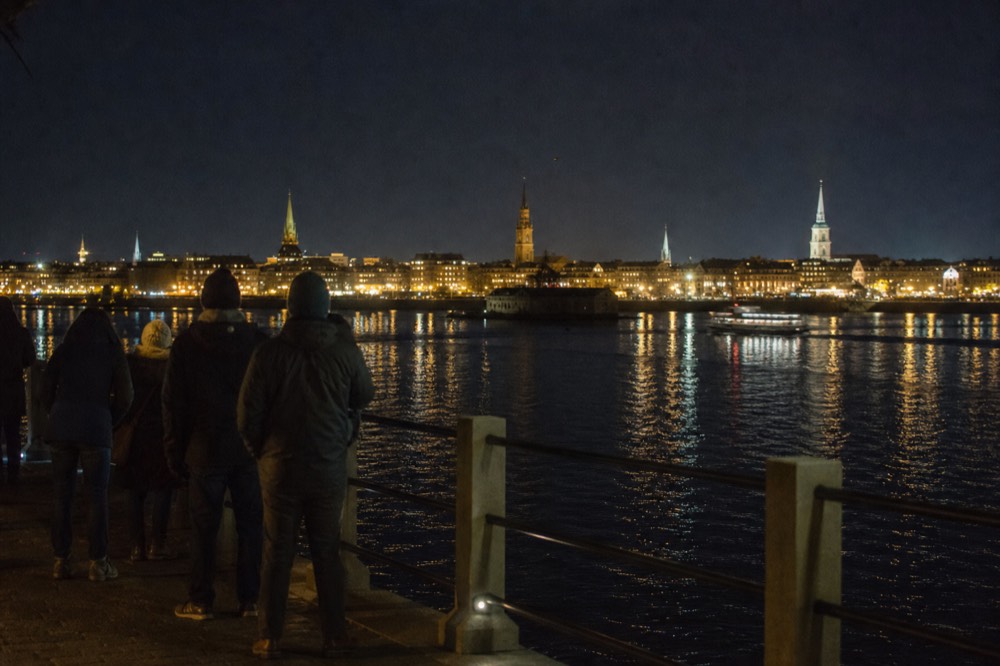 Charleston's city skyline and church steeples illuminated at night across dark water, no text, no logos, no people