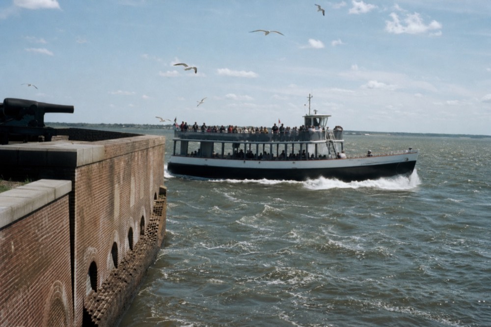 A passenger tour boat passing close to Fort Sumter in Charleston Harbor, no text, no logos, no people.