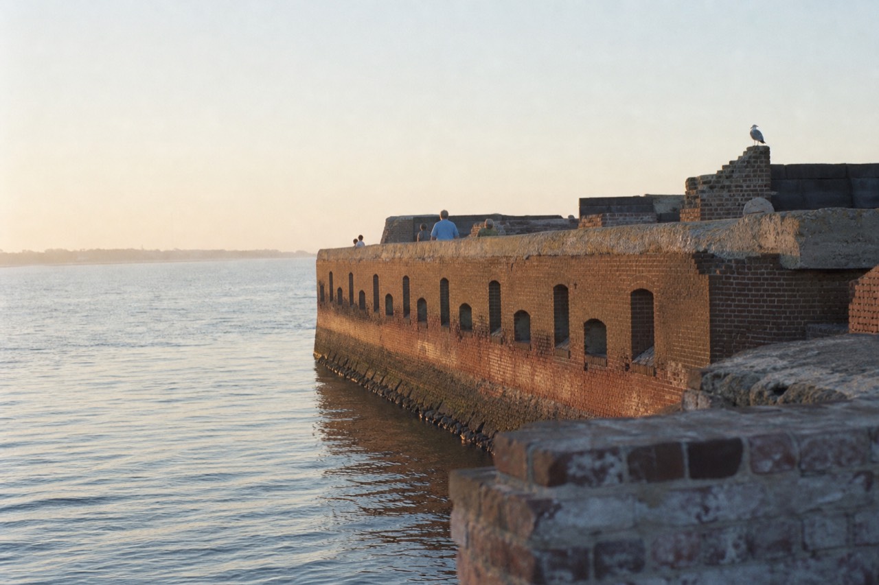 Fort Sumter's brick walls rising from Charleston Harbor at golden hour, no text, no logos, no people