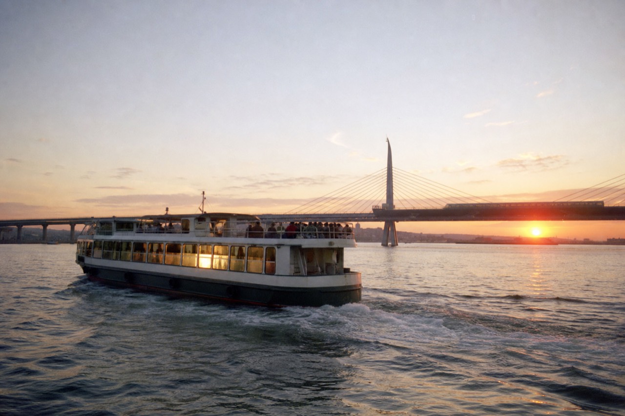 A sightseeing boat crossing Charleston harbor at golden hour with the Ravenel Bridge behind it, no text, no logos, no people.